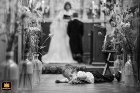   At Blakesley village church, a playful pageboy lays in the aisle engrossed with his toy during prayers, adding a sweet, lighthearted touch to the moment.